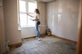 Female First Time Buyer Looking At House Survey In Room To Be Renovated