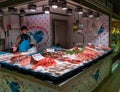 female fishmonger and market stall with fresh seafood in the Alicante market hall