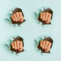 Female fist punching through blue paper background. War, struggle, conflict, feminist concept. Punchy pastel colors. Minimalist Royalty Free Stock Photo