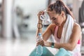 Female fit woman wipes out sweat and holds water bottle tired after overworking the gym session