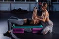 Female fitness instructor conducts personal training. Young attractive woman doing bench press lying on the platform