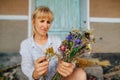 Female florist creates festive bouquets of dried flowers, focus on the composition of flowers in the hands of a woman. Creating