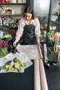 Female florist holding decorative Kraft beforehand making bouquet, in flower shop.