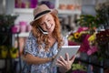 Female florist talking on mobile phone while using digital tablet Royalty Free Stock Photo