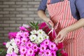 a female florist ties a ribbon bow on a bouquet of flowers wrapped in craft paper on the desktop. Top view. Royalty Free Stock Photo