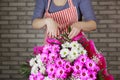 a female florist ties a ribbon bow on a bouquet of flowers wrapped in craft paper on the desktop. Top view. Royalty Free Stock Photo