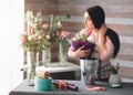 Female florist at work: pretty young dark-haired woman making fashion modern bouquet of different flowers. Women working Royalty Free Stock Photo