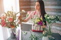 Female florist at work: pretty young dark-haired woman making fashion modern bouquet of different flowers. Women working Royalty Free Stock Photo