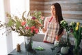 Female florist at work: pretty young dark-haired woman making fashion modern bouquet of different flowers. Women working Royalty Free Stock Photo