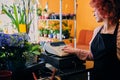 Female flower seller using cash register in a market shop.