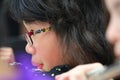 A female flutist playing a silver transverse flute indoors, profile view.