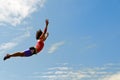 Female flying acrobat in front of blue sky Royalty Free Stock Photo