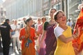 Female follower of Hare Krishna dancing and singing in bright yellow Sari dress outside in bright sunlight among the crowd