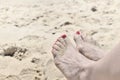 Female foot with red nail polish on the sand Royalty Free Stock Photo