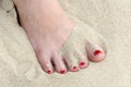 Female foot with red nail polish in the sand Royalty Free Stock Photo