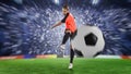 Female football player in orange uniform kicking the ball Royalty Free Stock Photo