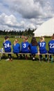 Female football team substitute players sitting on a bench watching Helsinki Cup tournament game