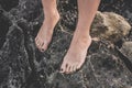 Female foots with painted nails on rocks close-up