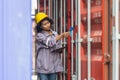 Female foreman dock worker working at shipping yard, Engineer in the hard hat with digital tablet inspecting container box Royalty Free Stock Photo