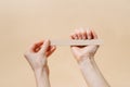 Female fragile hands make a natural manicure by filing nails with a file on a beige isolated background. Self care and beauty Royalty Free Stock Photo