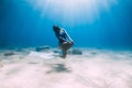 Female free diver with fins posing underwater in sea with sunlight