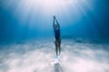 Female freediver dive with fins underwater in ocean with sunlight