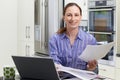 Female Freelance Worker Using Laptop In Kitchen At Home