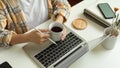 Female freelancer hands holding coffee cup while working with laptop on home office desk Royalty Free Stock Photo