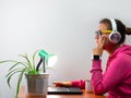 Female freelancer in headphones laptop Work from home, distance e-learning office. Pretty student girl drinking coffee Royalty Free Stock Photo