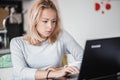 Female freelancer in her casual home clothing working remotly from her dining table in the morning. Home kitchen in the