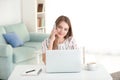 Female freelancer talking by phone while working on laptop in home office Royalty Free Stock Photo