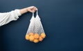 Female with fresh orange from garden in crochet bag