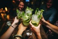 Female friends clinking glasses with mojito and lime at bar counter, Happy friends group cheering mojito drinks at cocktail bar