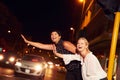 Female friends hailing taxi on city street at night Royalty Free Stock Photo