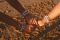 Female Friends Holding Hands Wearing Bracelets Hanging At Beach, Closeup