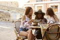 Female friends on holiday reading a guidebook outside a cafe