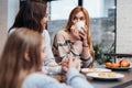 Female friends and a little girl sitting together at the kitchen table, drinking coffee and talking Royalty Free Stock Photo