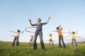 Female Friends Playing With Hula Hoop Against Sky In Park