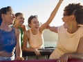 Female Friends Standing Up Through Sun Roof Car And Dancing On Road Trip Through Countryside Royalty Free Stock Photo