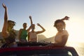 Female Friends Standing Up Through Sun Roof Car And Dancing On Road Trip Through Countryside Royalty Free Stock Photo