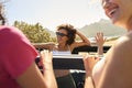 Female Friends Standing Up Through Sun Roof Car And Dancing On Road Trip Through Countryside Royalty Free Stock Photo