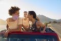 Female Friends Standing Up Through Sun Roof Car And Dancing On Road Trip Through Countryside Royalty Free Stock Photo