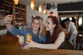 Female friends taking selfie with mobile phone while having drinks in bar Royalty Free Stock Photo