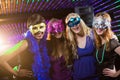 Female friends wearing masquerade in bar