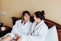 Female friends wearing white bathrobes relaxing in a hotel Royalty Free Stock Photo