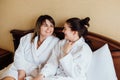 Female friends wearing white bathrobes relaxing in a hotel Royalty Free Stock Photo