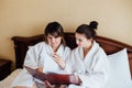 Female friends wearing white bathrobes relaxing in a hotel Royalty Free Stock Photo