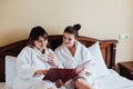 Female friends wearing white bathrobes relaxing in a hotel Royalty Free Stock Photo