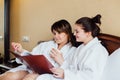 Female friends wearing white bathrobes relaxing in a hotel Royalty Free Stock Photo