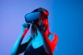 Female gamer using virtual reality headset and touching virtual interface in neon blue and red light, future technology concept Royalty Free Stock Photo